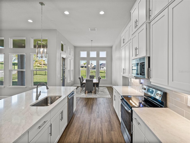 kitchen with dark wood finished floors, a sink, appliances with stainless steel finishes, tasteful backsplash, and a chandelier