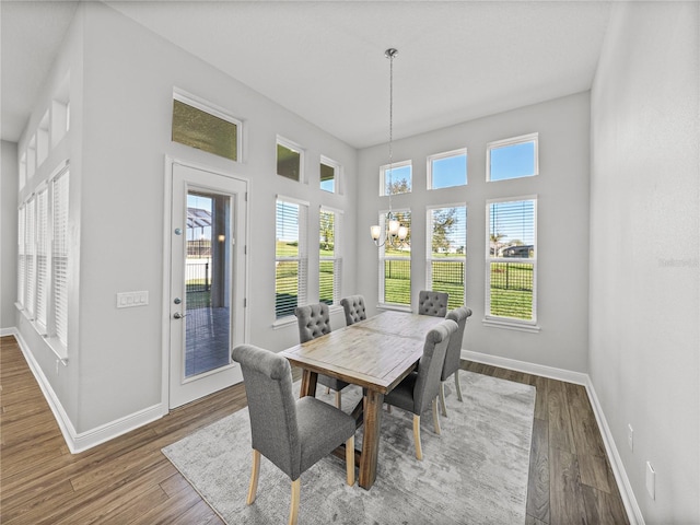 dining room with dark wood-type flooring, a notable chandelier, and baseboards