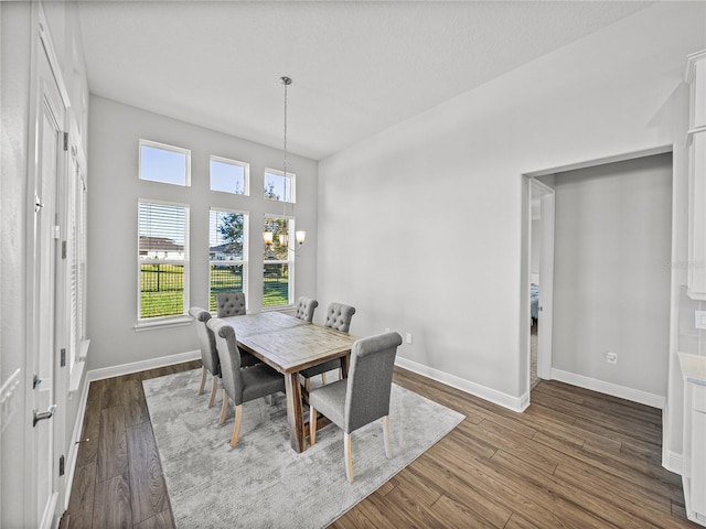 dining area with an inviting chandelier, baseboards, and dark wood-style flooring