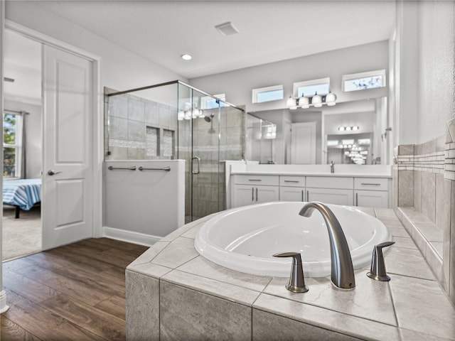 ensuite bathroom featuring vanity, wood finished floors, ensuite bath, a stall shower, and a bath