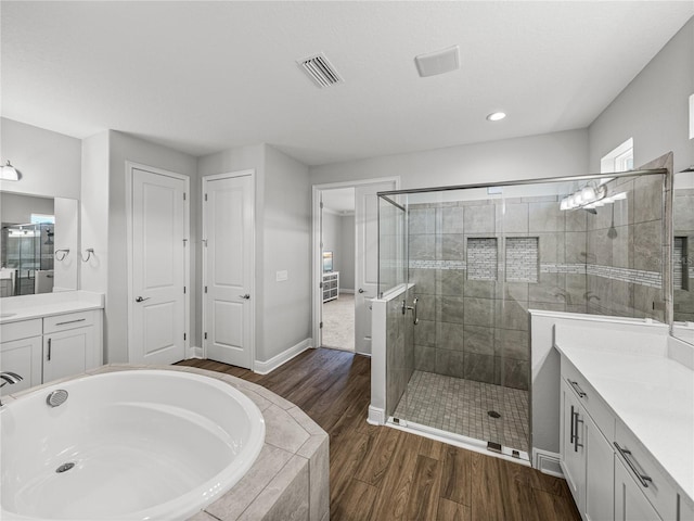 full bathroom featuring visible vents, a garden tub, a stall shower, wood finished floors, and vanity