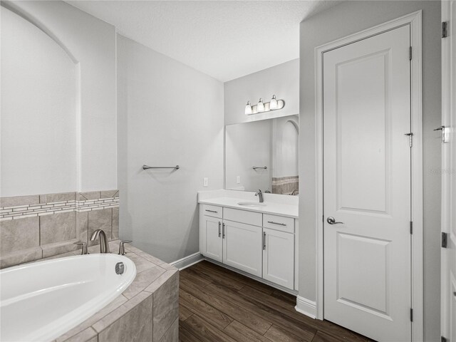 bathroom featuring vanity, a bath, wood finished floors, and baseboards