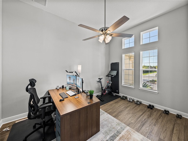 office area featuring visible vents, baseboards, dark wood-type flooring, and a ceiling fan