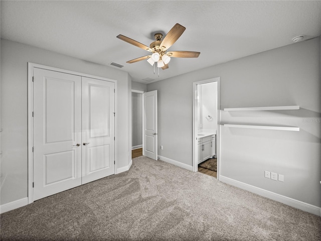 unfurnished bedroom featuring carpet, visible vents, baseboards, ensuite bath, and a closet