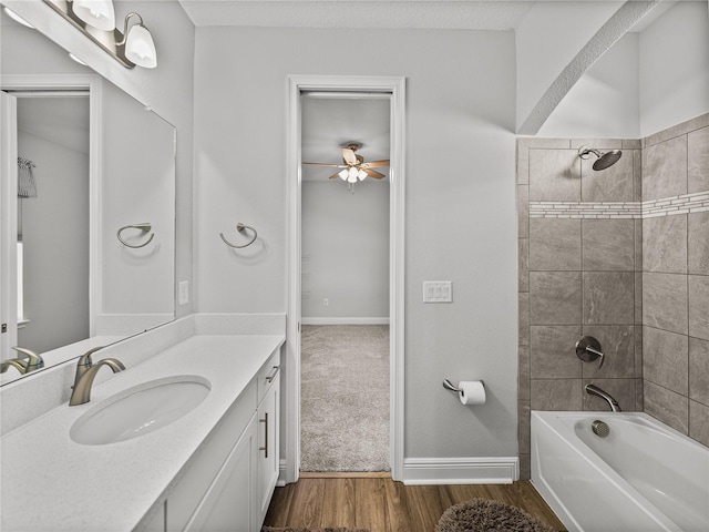 full bath with baseboards, shower / tub combination, wood finished floors, vanity, and a ceiling fan