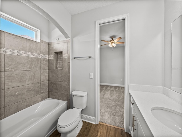 bathroom featuring toilet, a ceiling fan, wood finished floors, baseboards, and vanity