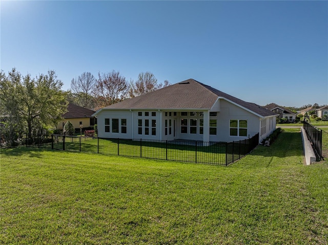 rear view of house featuring a yard, a fenced backyard, and a shingled roof