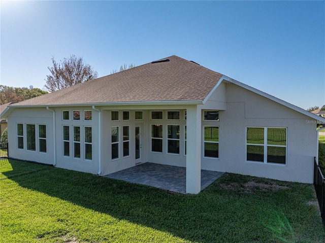 back of property featuring fence, roof with shingles, stucco siding, a yard, and a patio