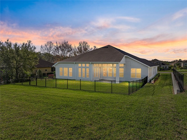 rear view of property with a yard, a fenced backyard, and a shingled roof