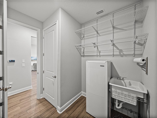 washroom featuring visible vents, washer / clothes dryer, wood finished floors, baseboards, and laundry area