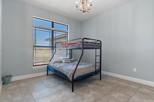 tiled bedroom with baseboards and a chandelier