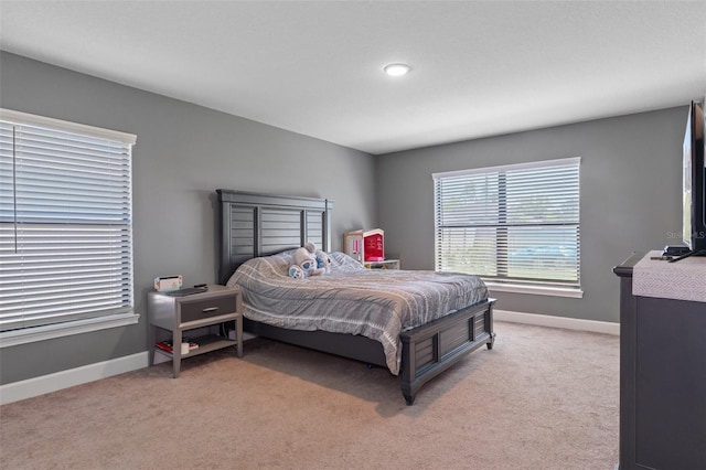 bedroom with baseboards and light colored carpet