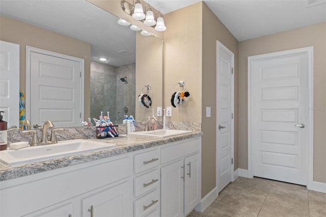 bathroom with a shower stall, double vanity, tile patterned floors, and a sink