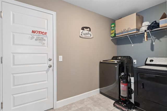 laundry room featuring baseboards, light tile patterned flooring, laundry area, and washing machine and clothes dryer