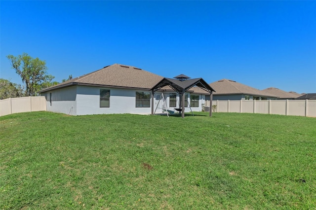 rear view of house featuring a gazebo, a yard, and fence