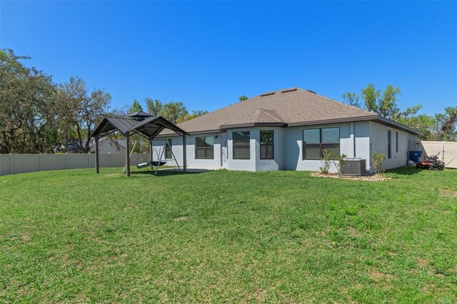 back of house featuring cooling unit, a yard, and a fenced backyard