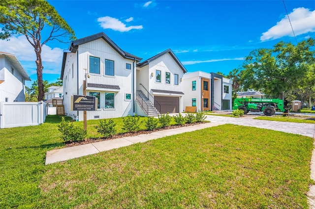 view of front of property with a front lawn, decorative driveway, fence, stairway, and an attached garage