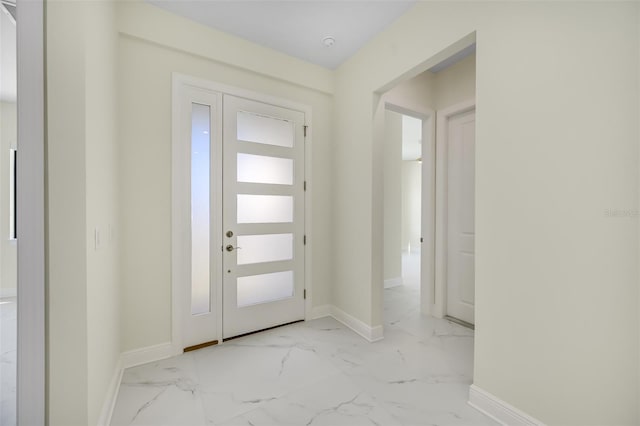 foyer with baseboards and marble finish floor