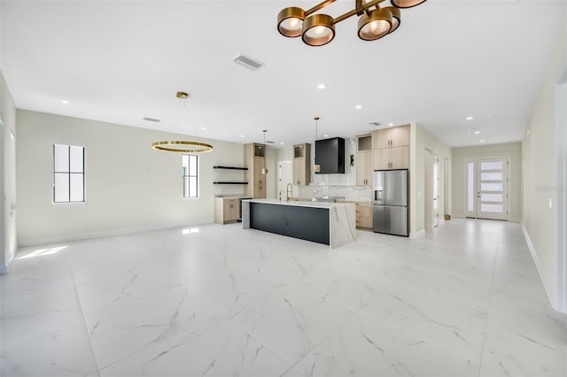 kitchen featuring visible vents, modern cabinets, an island with sink, stainless steel refrigerator with ice dispenser, and open floor plan