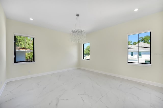 empty room featuring a notable chandelier, recessed lighting, marble finish floor, and baseboards