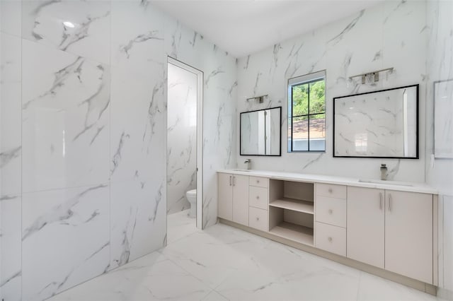 bathroom with a sink, toilet, marble finish floor, and double vanity