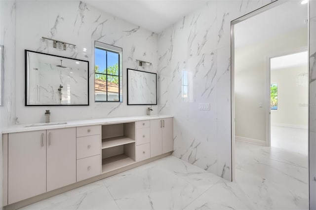 bathroom featuring a sink, stone wall, marble finish floor, and double vanity