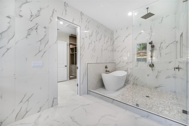 full bath featuring stone wall, a marble finish shower, a freestanding bath, a spacious closet, and marble finish floor