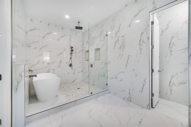 bathroom with a marble finish shower, a soaking tub, marble finish floor, and stone wall