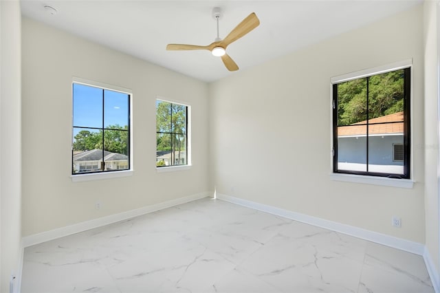 empty room with baseboards, marble finish floor, and a ceiling fan