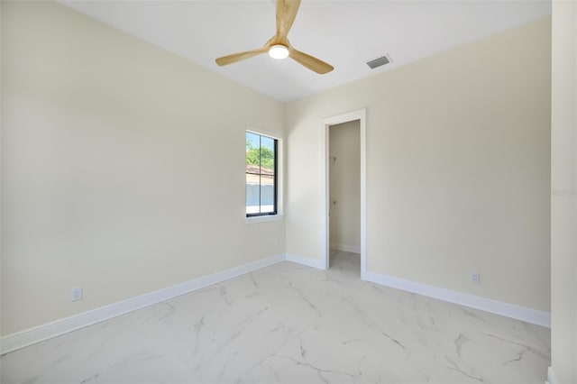 empty room with visible vents, baseboards, marble finish floor, and a ceiling fan