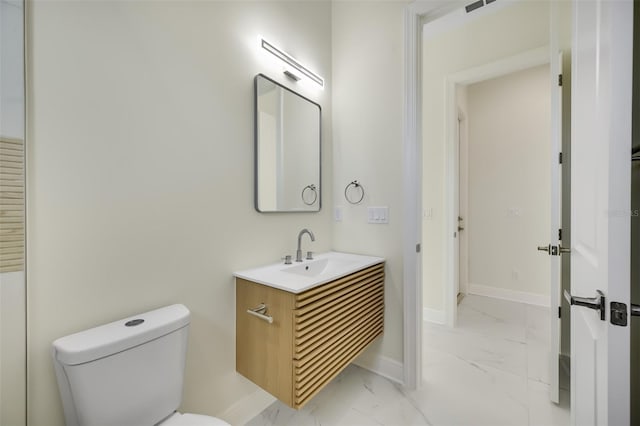 half bathroom with baseboards, toilet, marble finish floor, and vanity