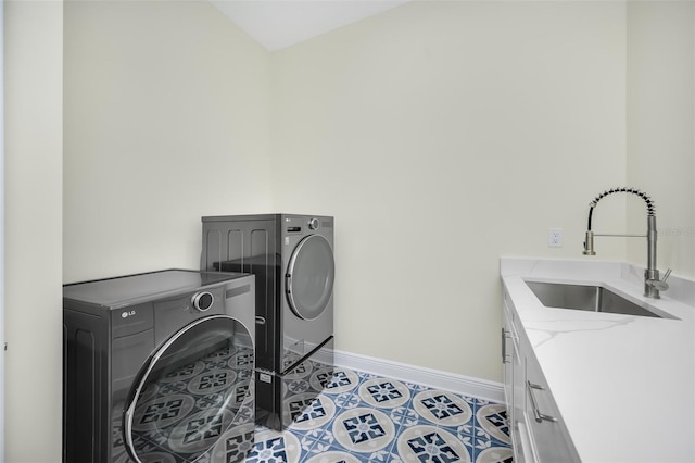 laundry area with light tile patterned floors, baseboards, separate washer and dryer, cabinet space, and a sink