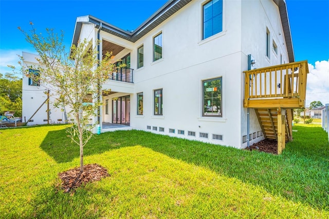 back of house featuring stucco siding, a yard, crawl space, a balcony, and stairs