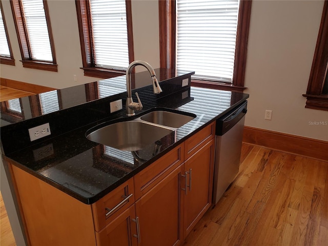 kitchen featuring light wood finished floors, a sink, baseboards, stainless steel dishwasher, and a kitchen island with sink