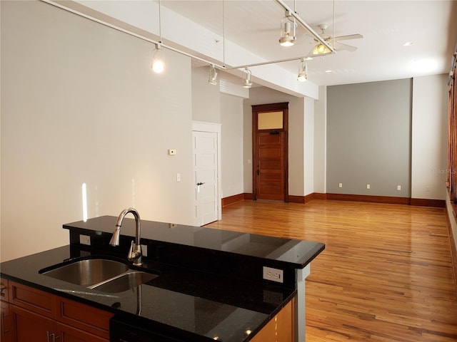 kitchen with baseboards, open floor plan, dishwasher, light wood-style flooring, and a sink