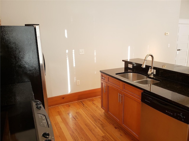 kitchen with baseboards, light wood-style flooring, brown cabinets, stainless steel appliances, and a sink