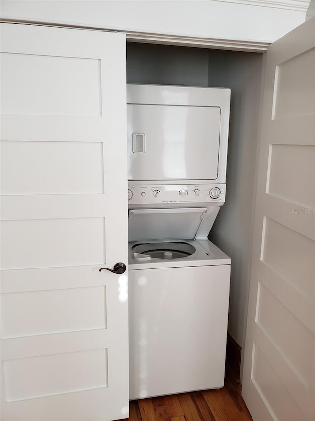 laundry room featuring dark wood finished floors, laundry area, and stacked washer / drying machine