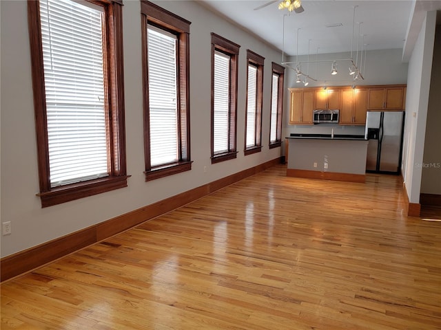 unfurnished living room featuring a healthy amount of sunlight, baseboards, and light wood-style floors