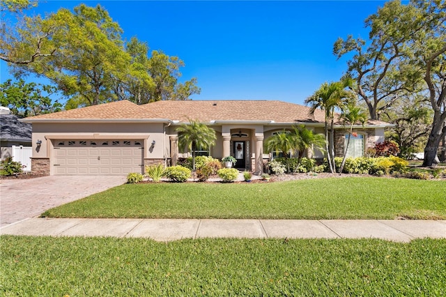 ranch-style house featuring stucco siding, an attached garage, decorative driveway, and a front yard