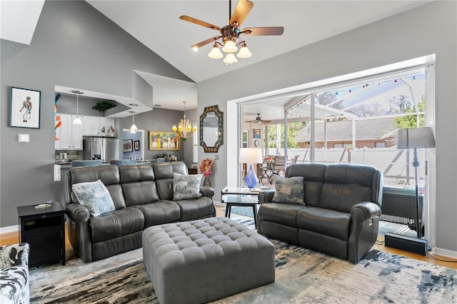 living area with light wood-type flooring, baseboards, high vaulted ceiling, and ceiling fan with notable chandelier