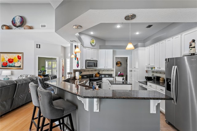 kitchen featuring visible vents, a peninsula, stainless steel appliances, white cabinetry, and open floor plan