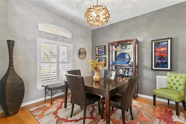 dining space with visible vents, wood finished floors, and baseboards