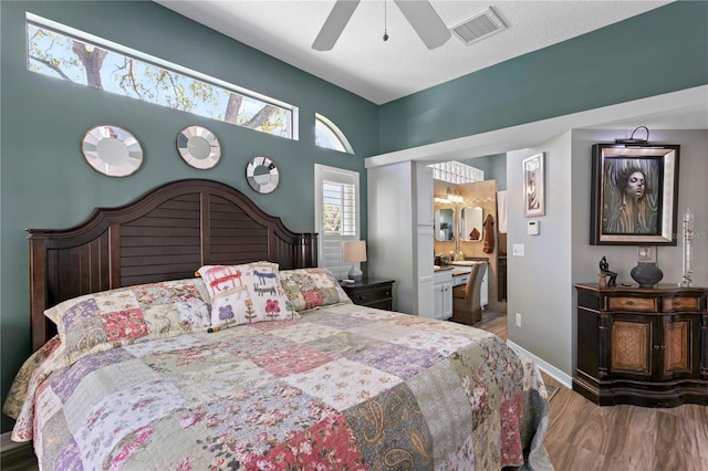 bedroom with light wood-type flooring, visible vents, ensuite bath, baseboards, and ceiling fan