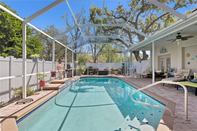 view of pool with a patio, a fenced backyard, french doors, glass enclosure, and ceiling fan