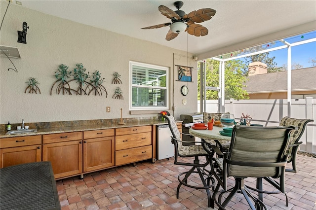 dining space with a ceiling fan, a textured wall, and brick floor