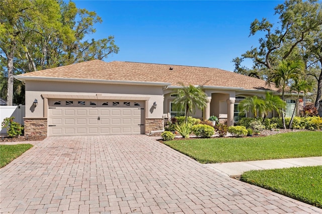 view of front of property featuring decorative driveway, stone siding, a garage, and stucco siding