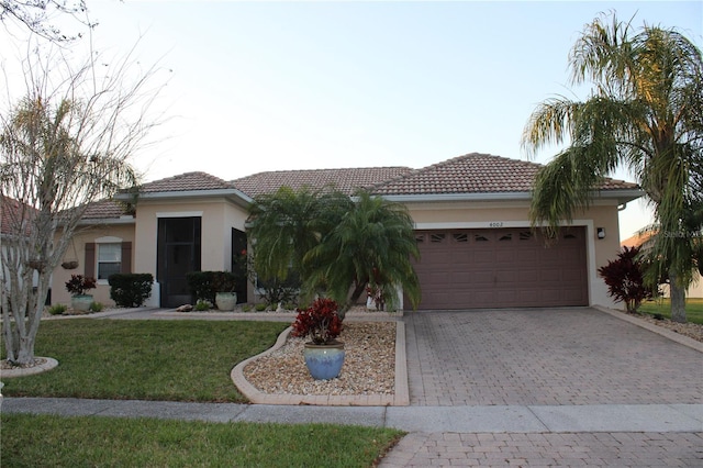 view of front of property with decorative driveway, a front yard, an attached garage, and stucco siding