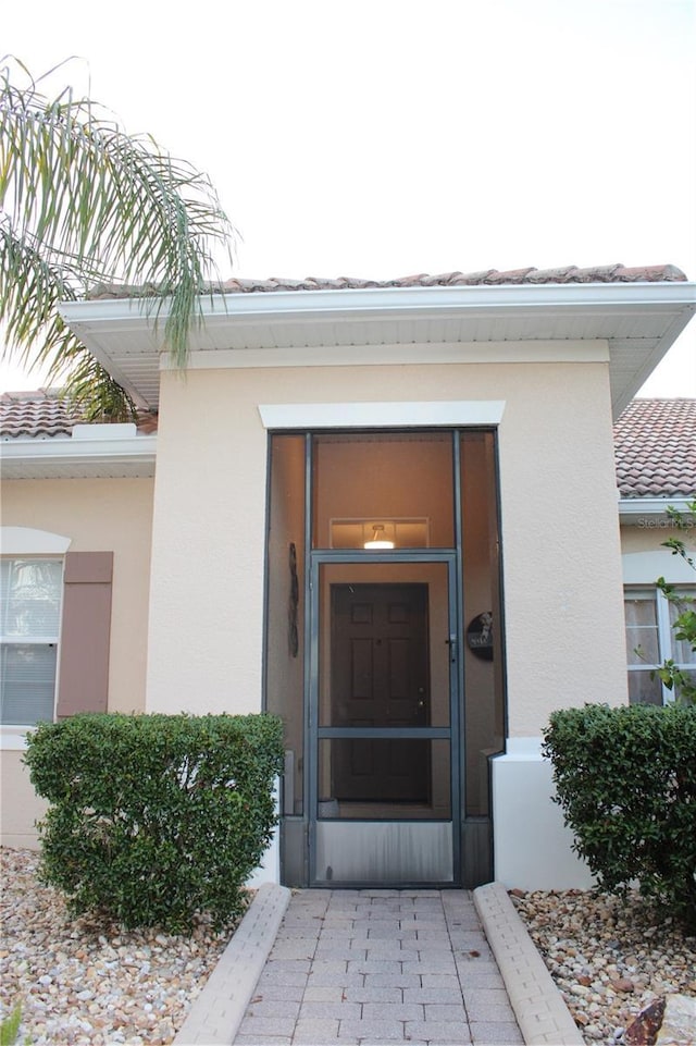 doorway to property with a tile roof and stucco siding