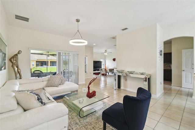 living room featuring light tile patterned floors, visible vents, arched walkways, and ceiling fan