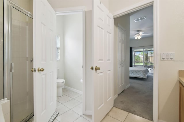 bathroom featuring toilet, tiled shower, tile patterned floors, vanity, and a ceiling fan